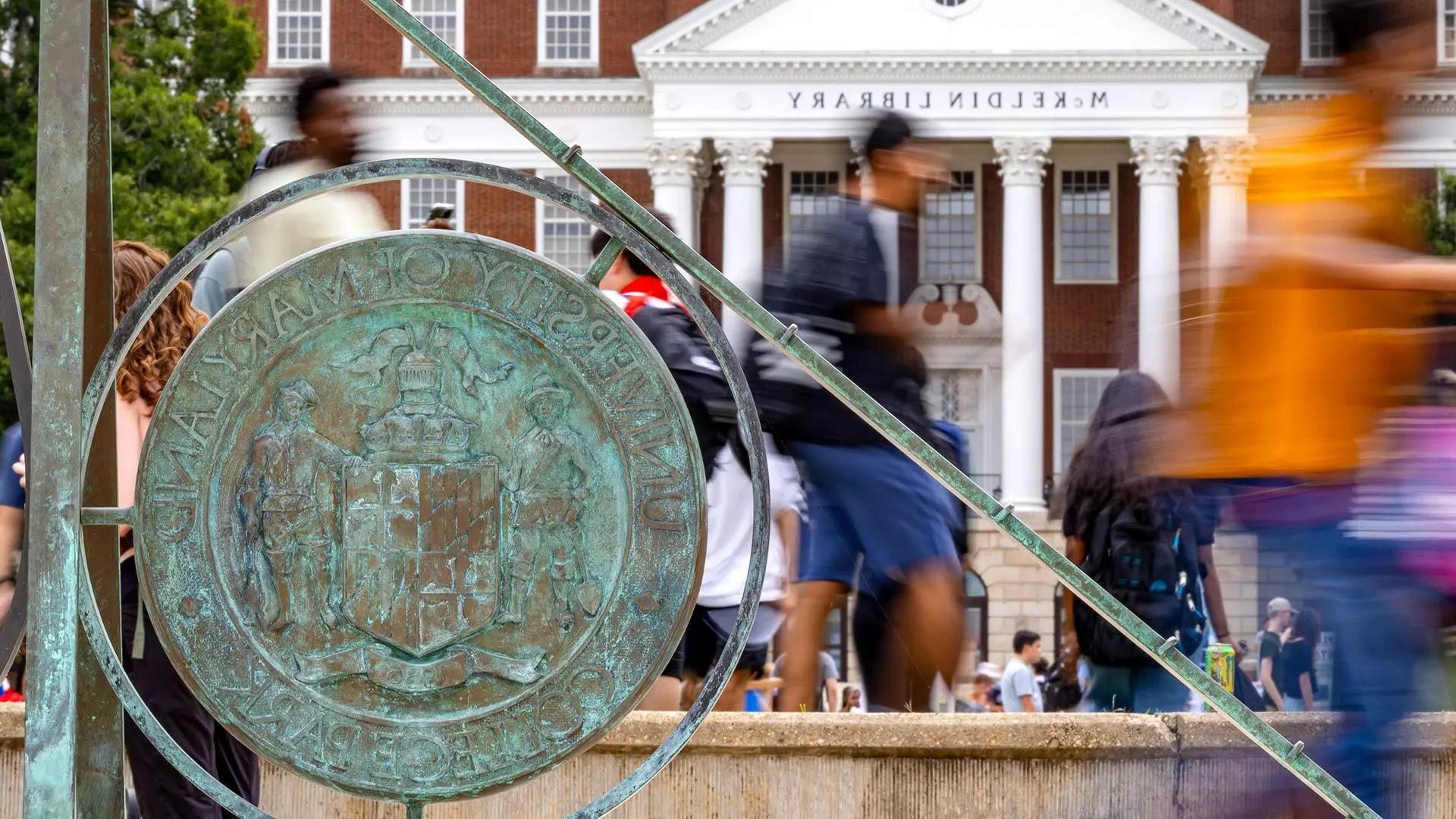 Students, blurred, walk by the sundial on McKeldin mall